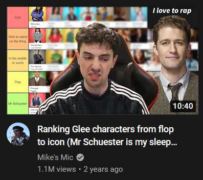 youtube thumbnail of a video by mike's mic, from two years ago. a man, presumably mike, is sitting looking disgusted in the centre of the thumbnail. next to him is an image of will schuester looking soullessly towards the camera. above will, in white text, are those fateful words: i love to rap.